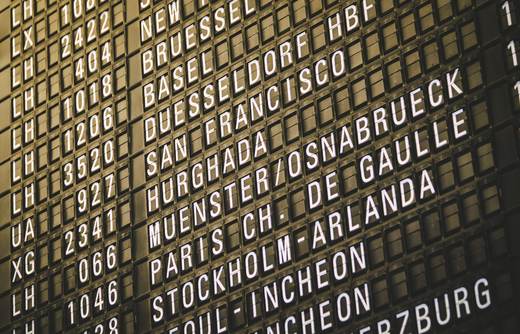 A split-flap airport departure board listing flights to Brussels, San Francisco, Paris and Stockholm