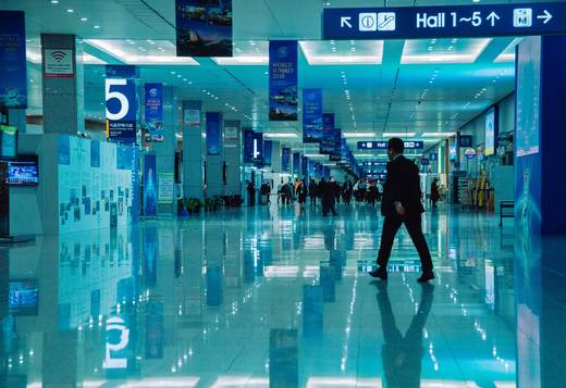 A delegate crosses the concourse of a convention centre beneath Hall 1-5 signage and summit banners