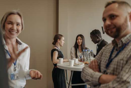Delegates with lanyards talk over coffee during a conference break