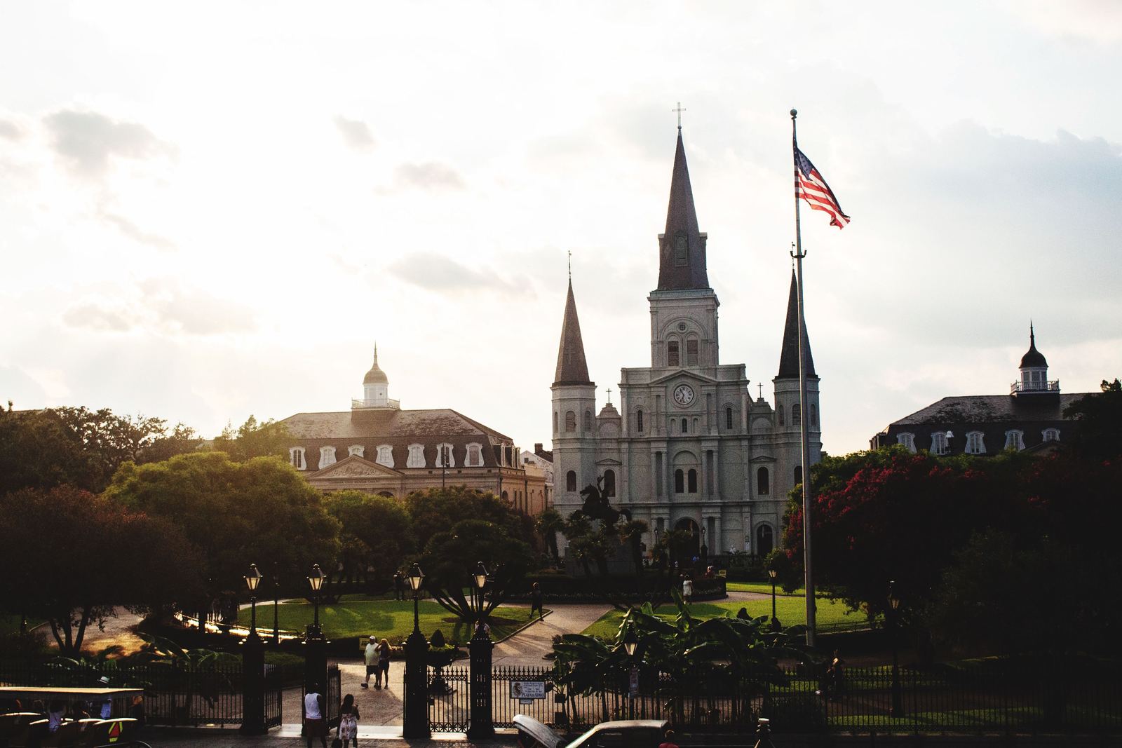 St. Louis Cathedral rising above Jackson Square in New Orleans at dusk, with an American flag on a pole