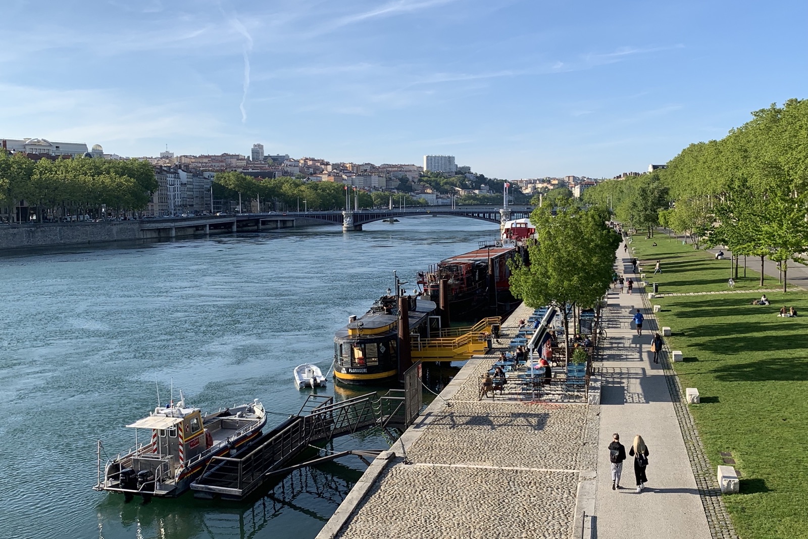 The Rhône riverbank promenade in Lyon with moored barges and the Presqu'île beyond