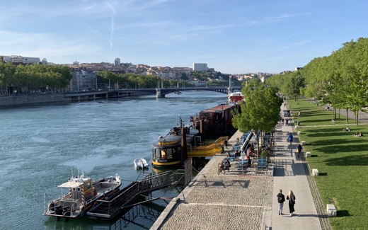 The Rhône riverbank promenade in Lyon with moored barges and the Presqu'île beyond