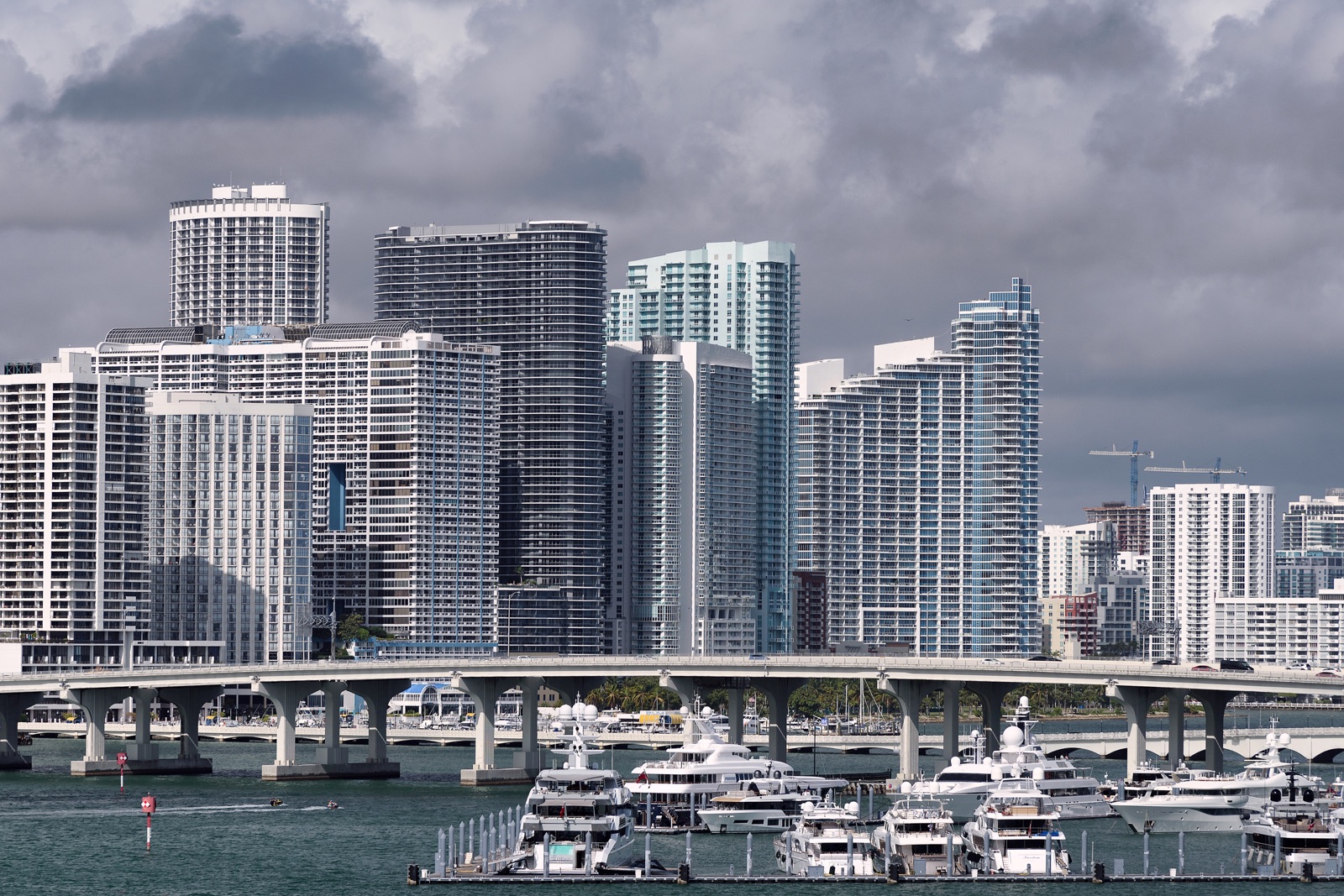 Miami high-rise towers across Biscayne Bay, with yachts moored at a marina