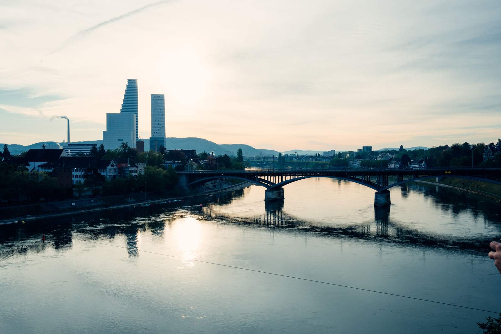 The Basel skyline and the Rhine at dusk, with the Roche towers on the horizon