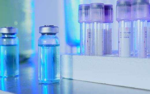 Glass vials and racked sample tubes in a blue-lit testing laboratory