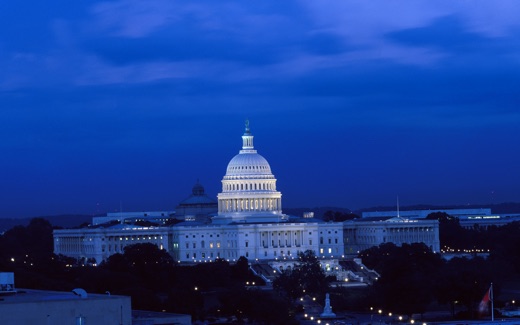 The US Capitol dome illuminated against a deep blue night sky