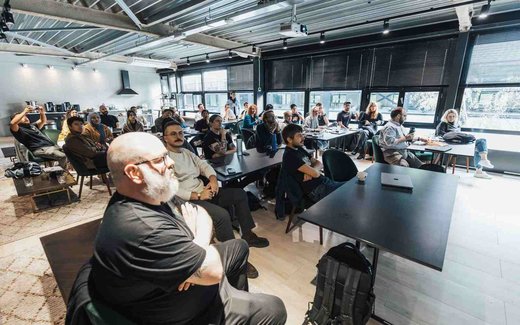 Attendees seated at tables in a bright, modern meeting space during a group presentation