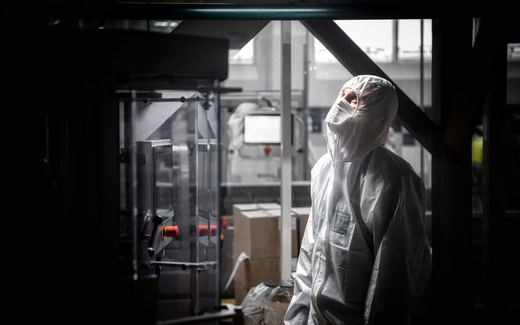 A worker in white sterile coveralls beside equipment on a pharmaceutical production line