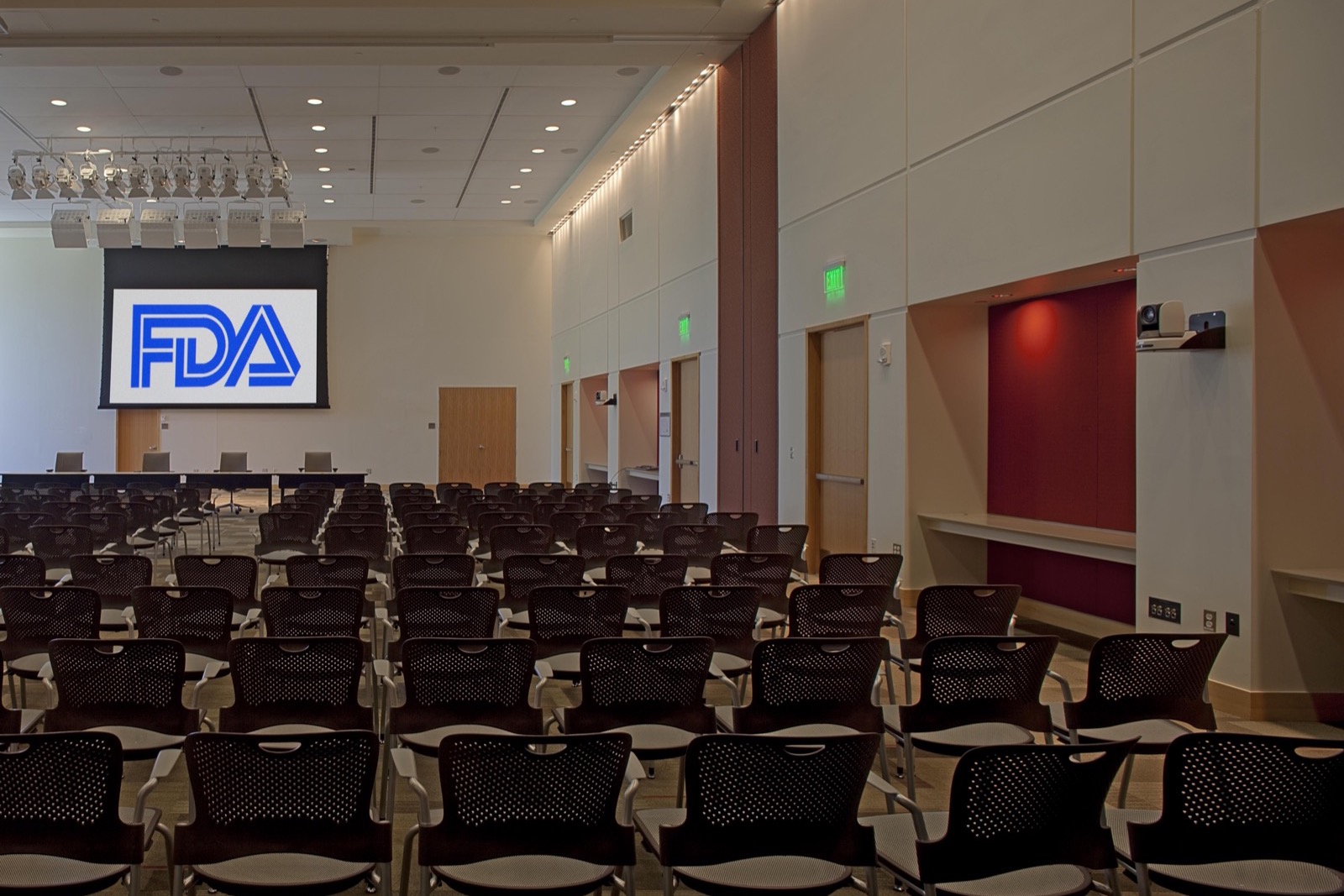 Rows of empty chairs facing a projection screen showing the FDA logo in the White Oak Great Room