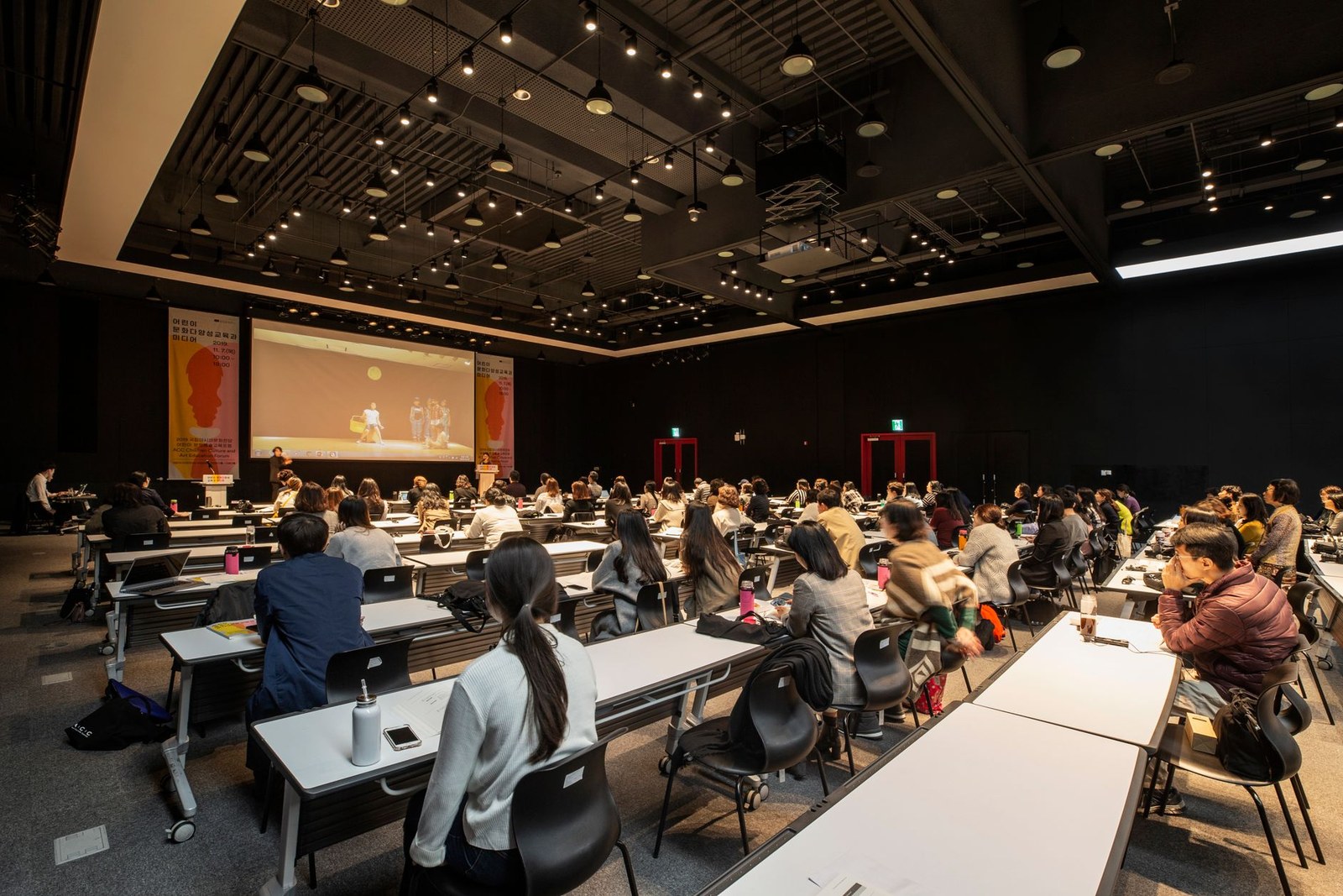 Rows of seated attendees watching a presentation in a modern conference hall