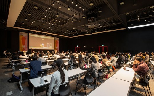 Rows of seated attendees watching a presentation in a modern conference hall
