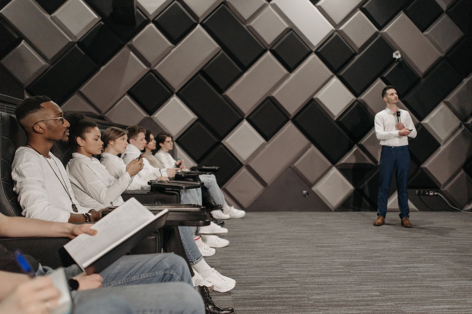 Delegates seated in a modern conference room listening to a presenter on stage