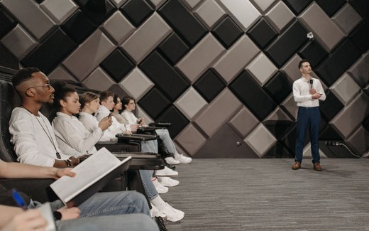 Delegates seated in a modern conference room listening to a presenter