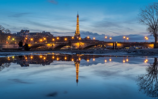 The Eiffel Tower and Pont des Invalides at dusk, reflected in still water