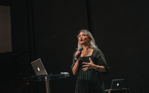 A woman speaking into a microphone while presenting from a stage