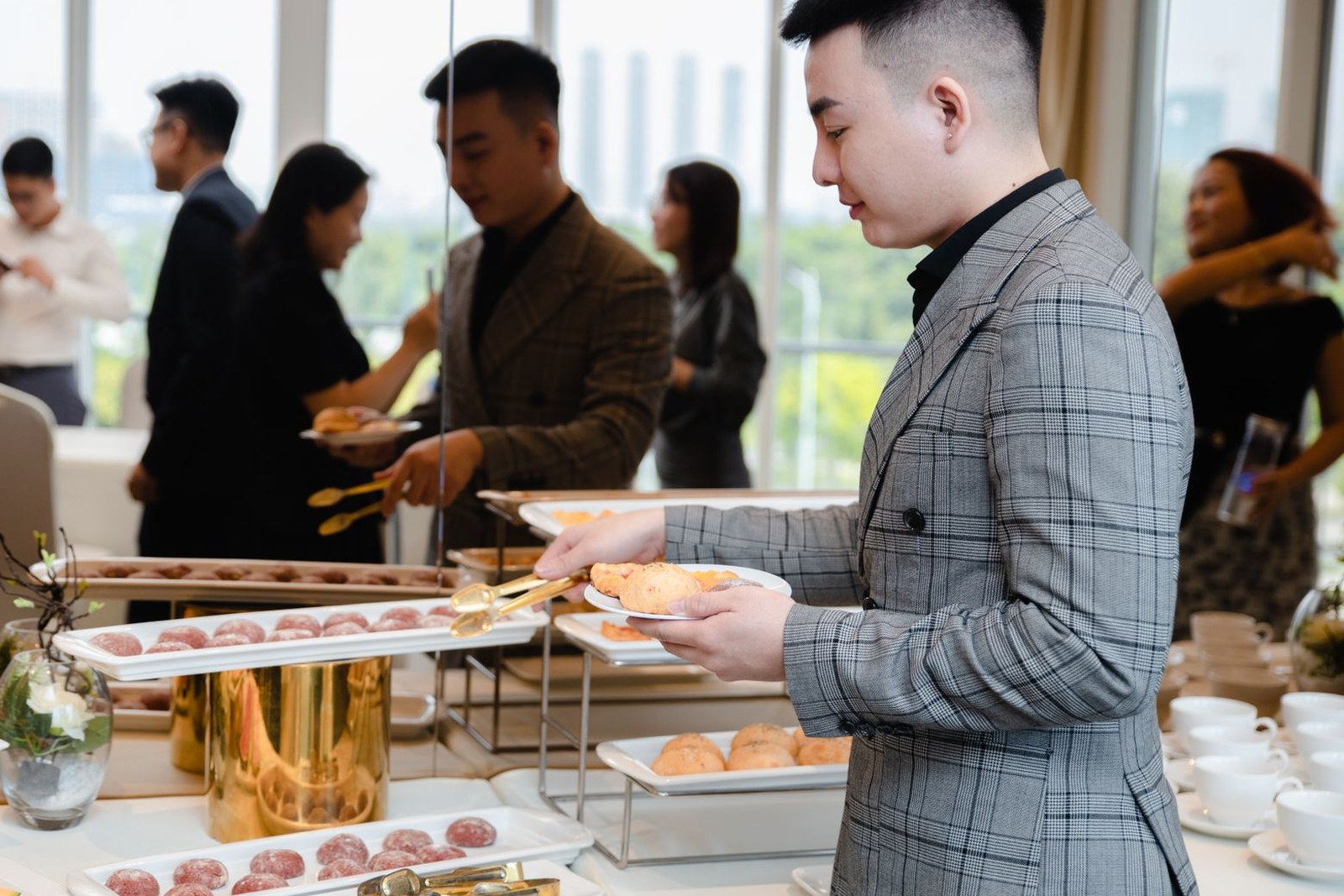 Conference attendees in business attire serve themselves from a buffet table at a professional event