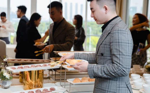 Conference attendees in business attire serve themselves from a buffet table at a professional event