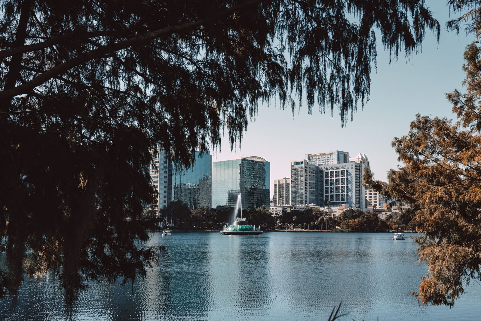 Downtown Orlando high-rises and the Lake Eola fountain framed by cypress trees
