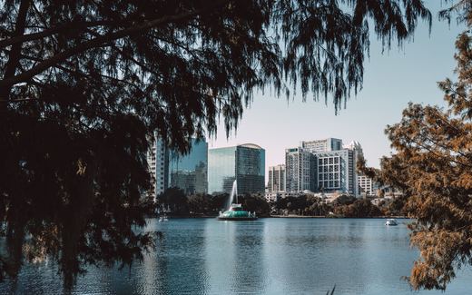Downtown Orlando high-rises and the Lake Eola fountain framed by cypress trees
