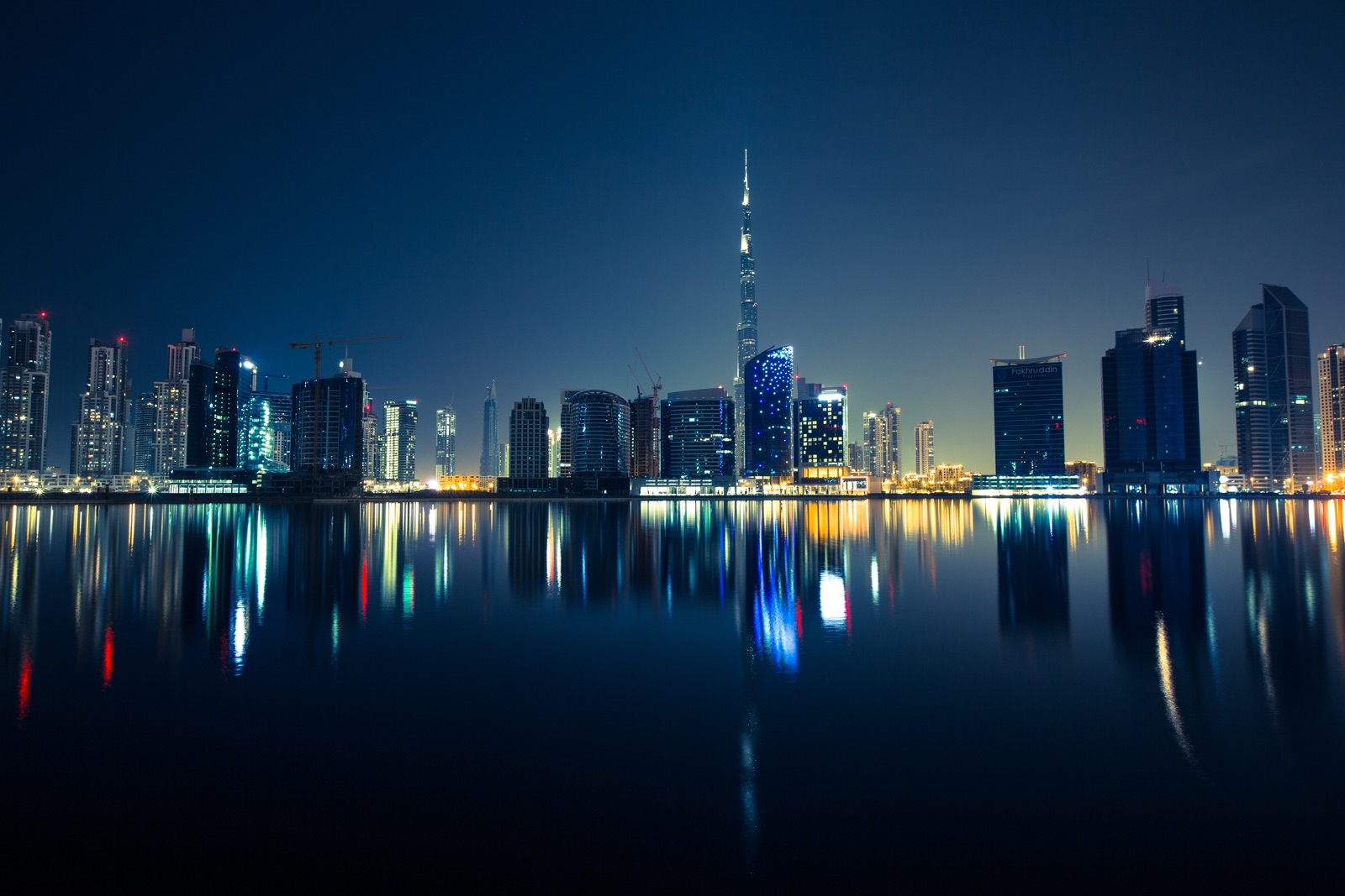 The Dubai skyline at night with the Burj Khalifa reflected in still water